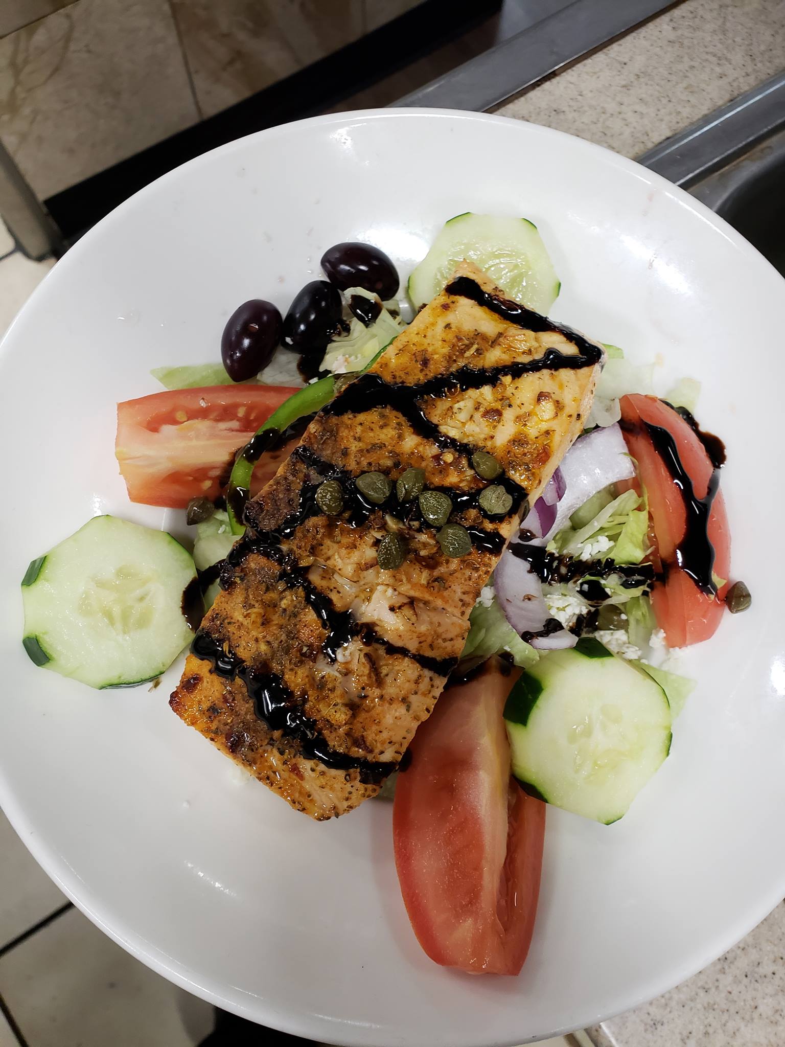 A plate of salmon with tomato and cucumber slices