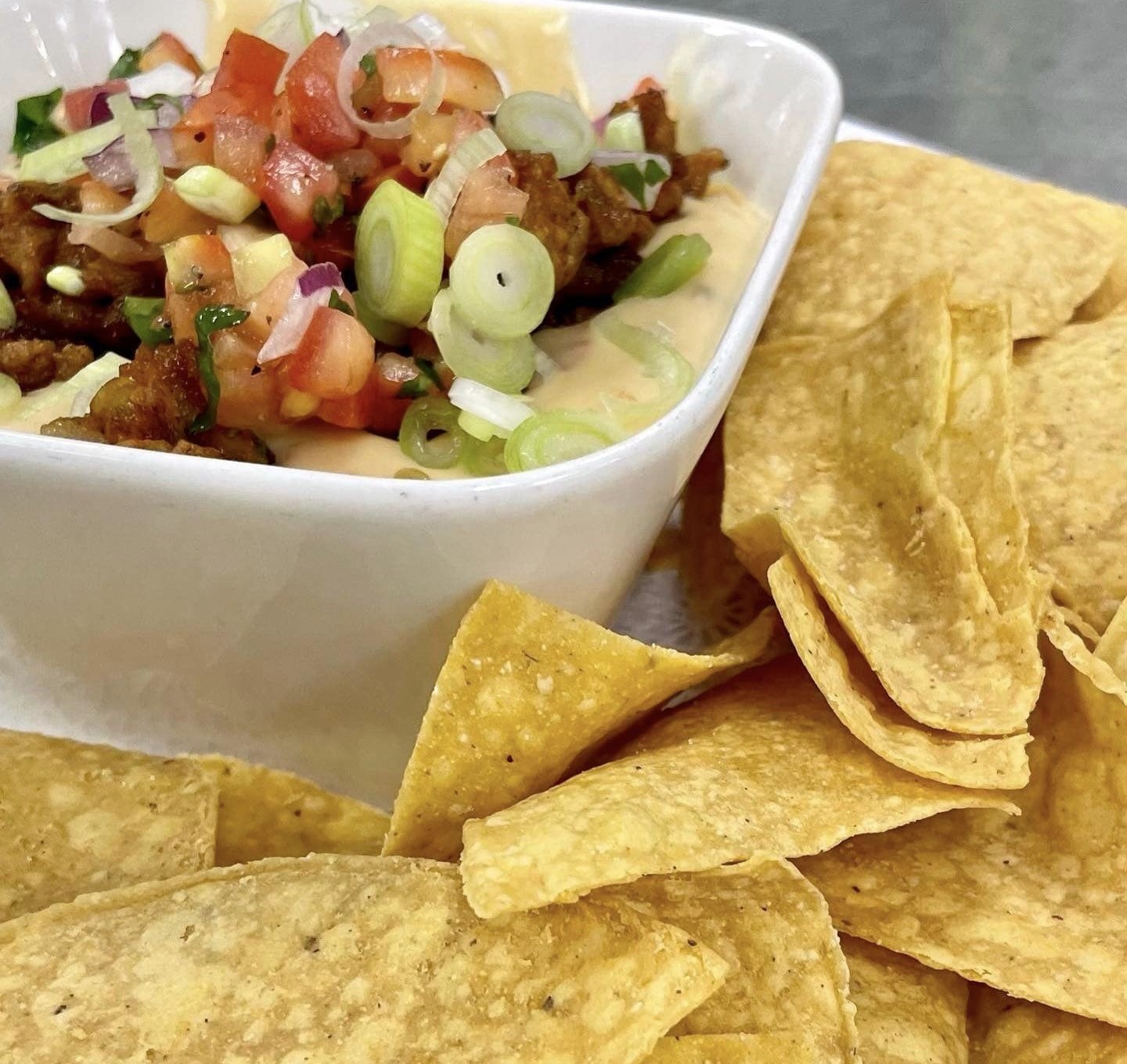 A plate of chips with a queso and pico de gallo dip
