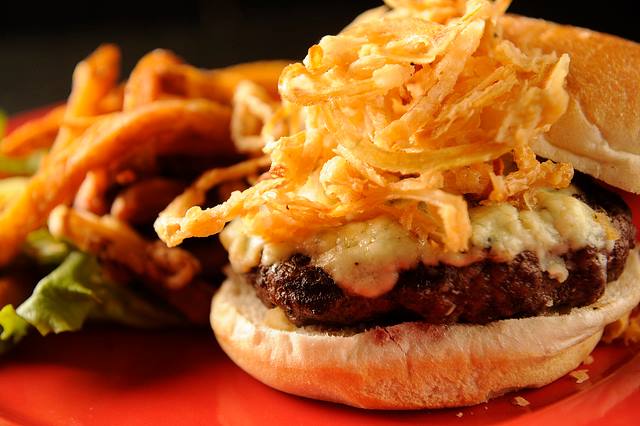 a burger with onion rings on top