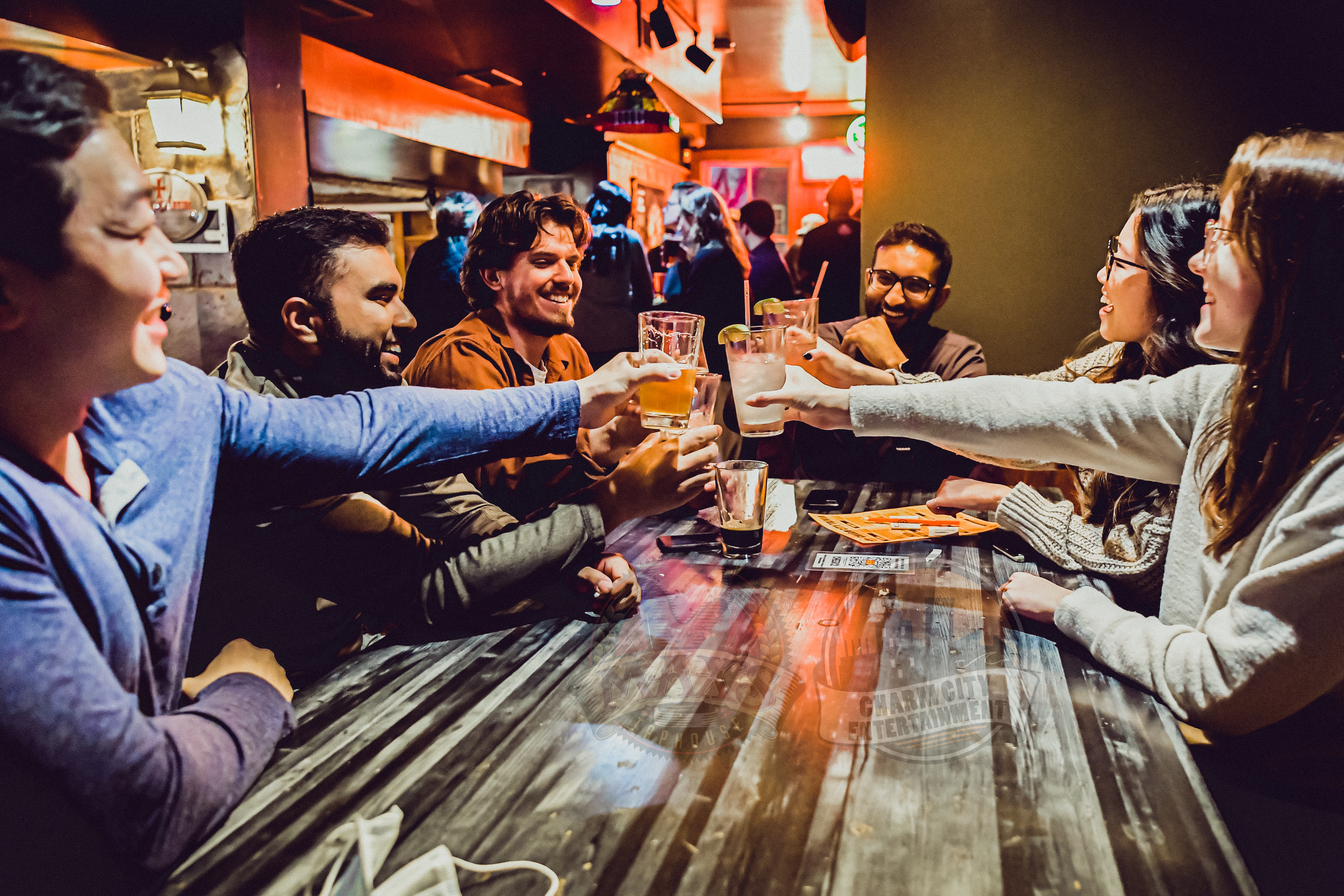 a trivia team sitting around a table cheersing their glasses