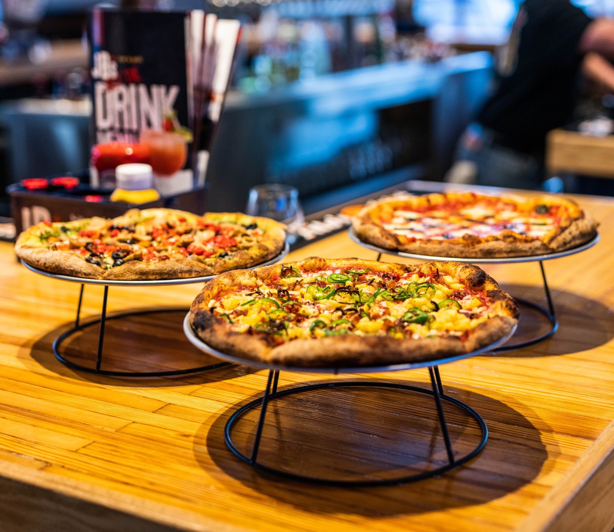 three 12 inch pizzas on stands on a counter