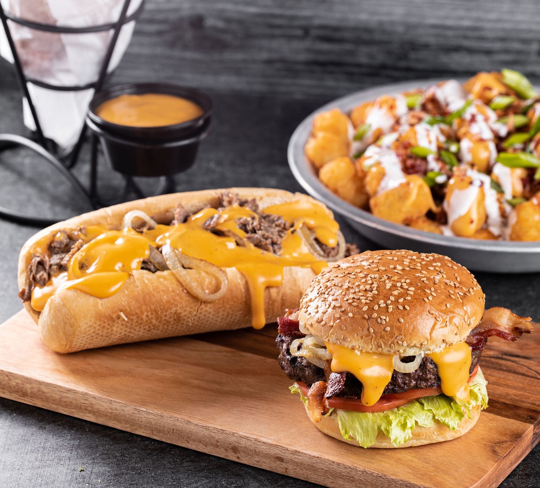 a burger, loaded tots, and a cheesesteak sandwich