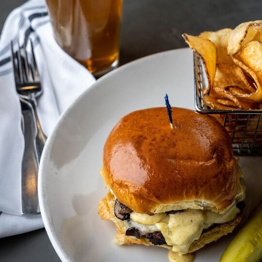 a burger with fresh potato chips and a glass of beer
