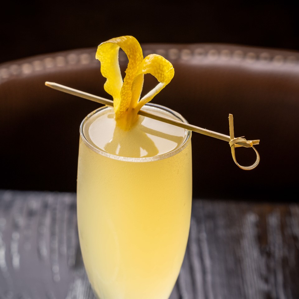a mimosa with a lemon peel garnish