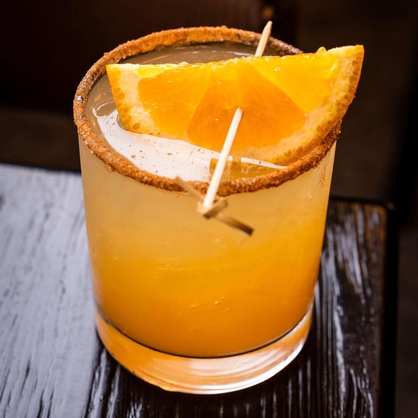 an orange cocktail with a rim and an orange wedge