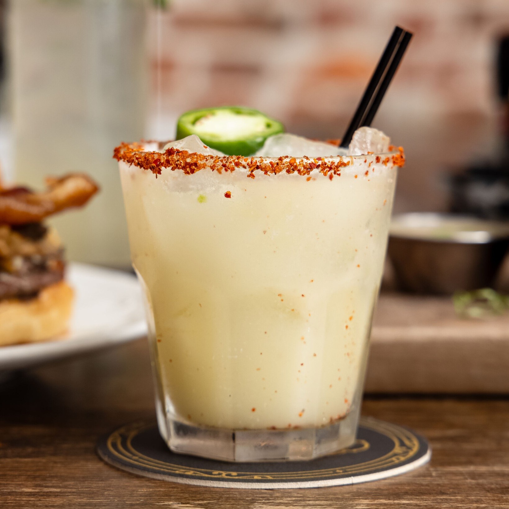 a Spicy Pineapple Margarita with a jalapeno slice and a straw
