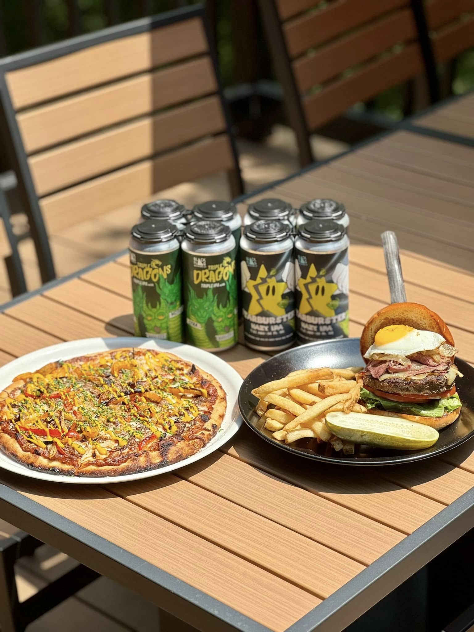 a plate of Big Strami Burger, a plate of Don Pablo Pizza, and cans of Triple Dragons and Starburster