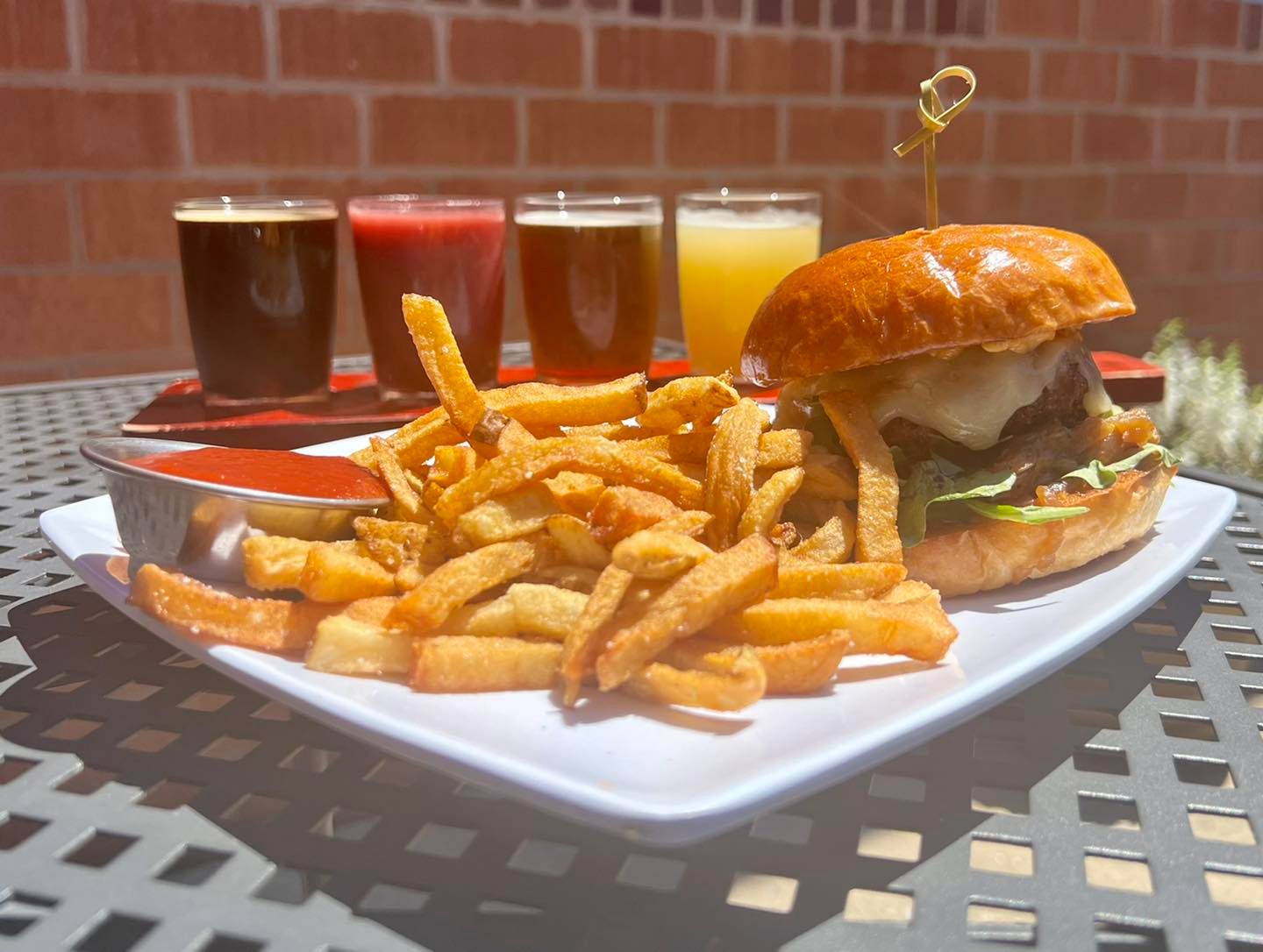 a burger with fries and a flight of beer