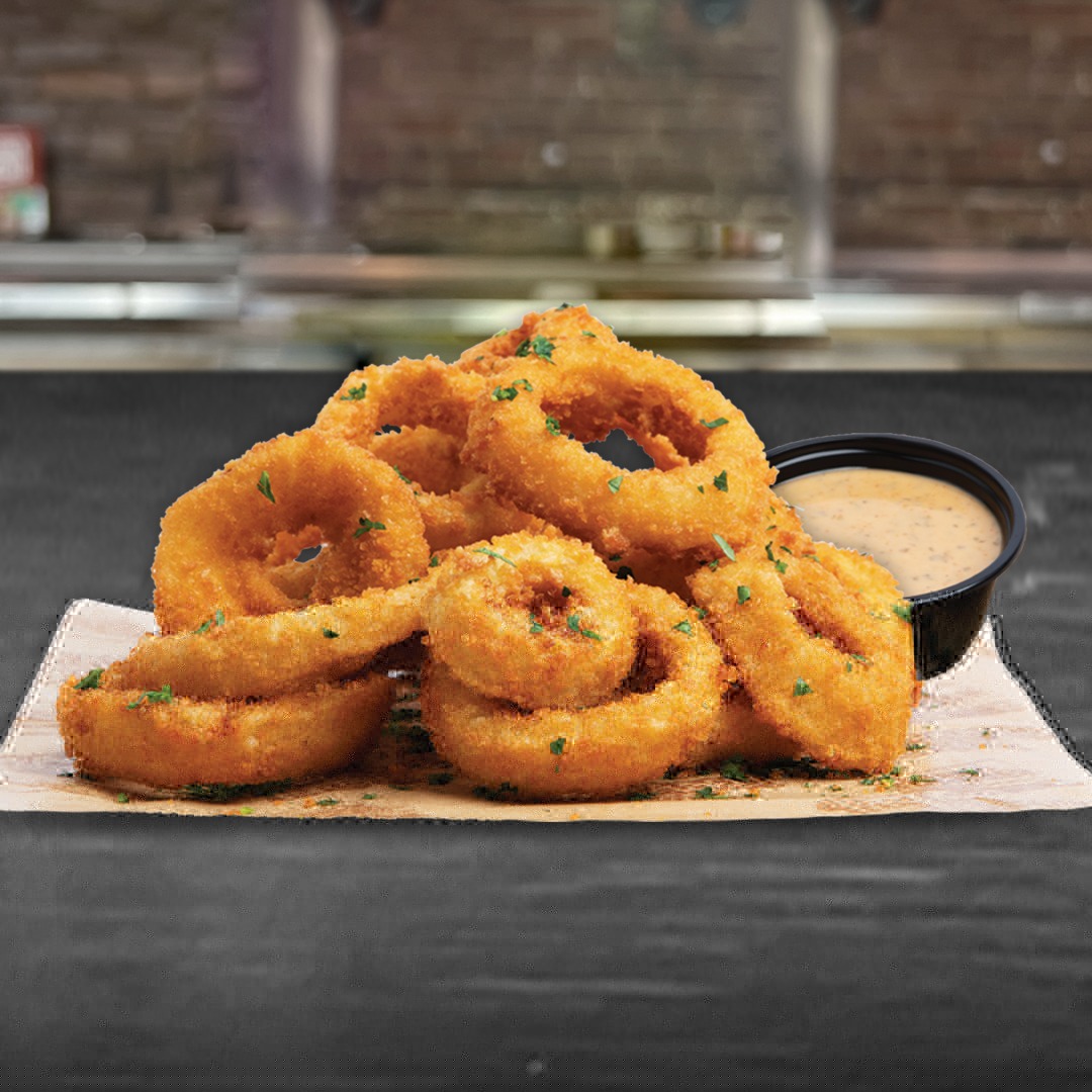 a pile of onion rings with dip
