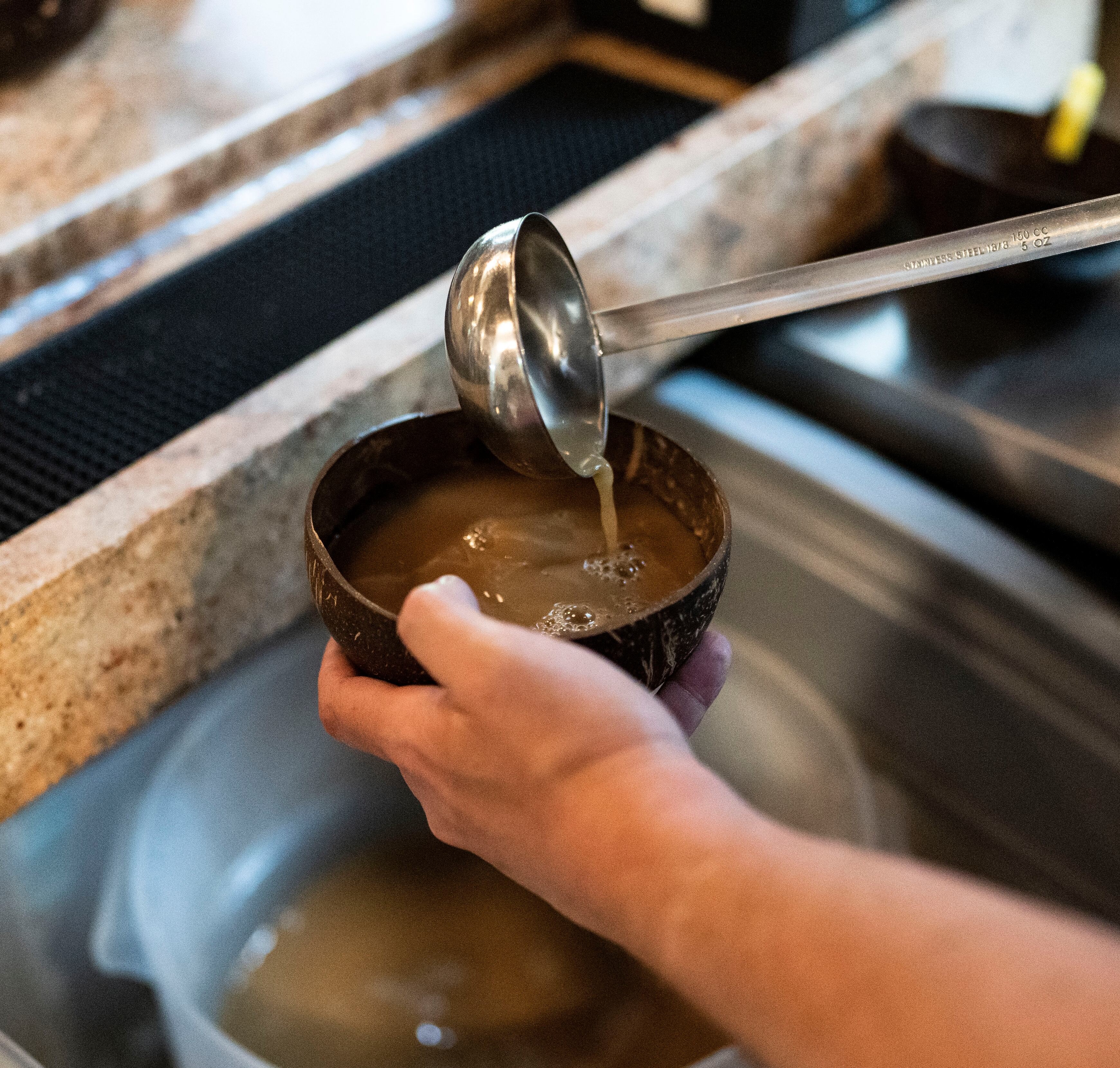 a person pouring Kava into a cup