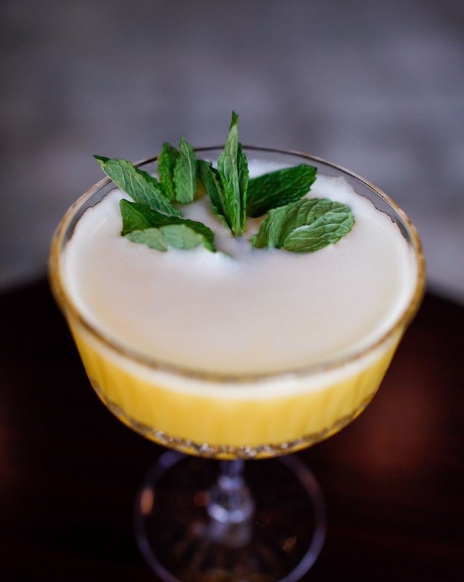 a yellow cocktail with mint