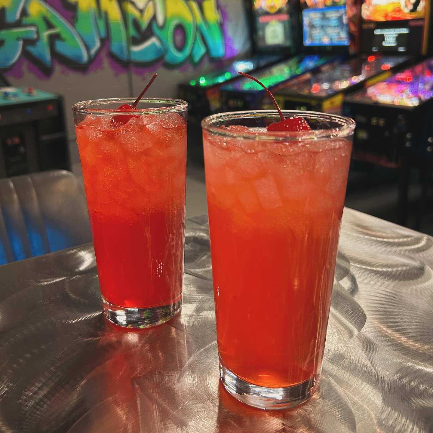 two red cocktails with cherries on a table