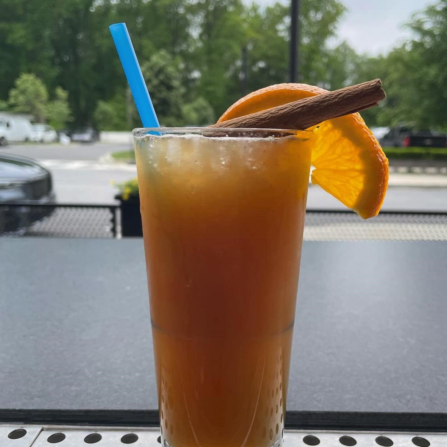 an orange cocktail with an orange wedge and cinnamon stick