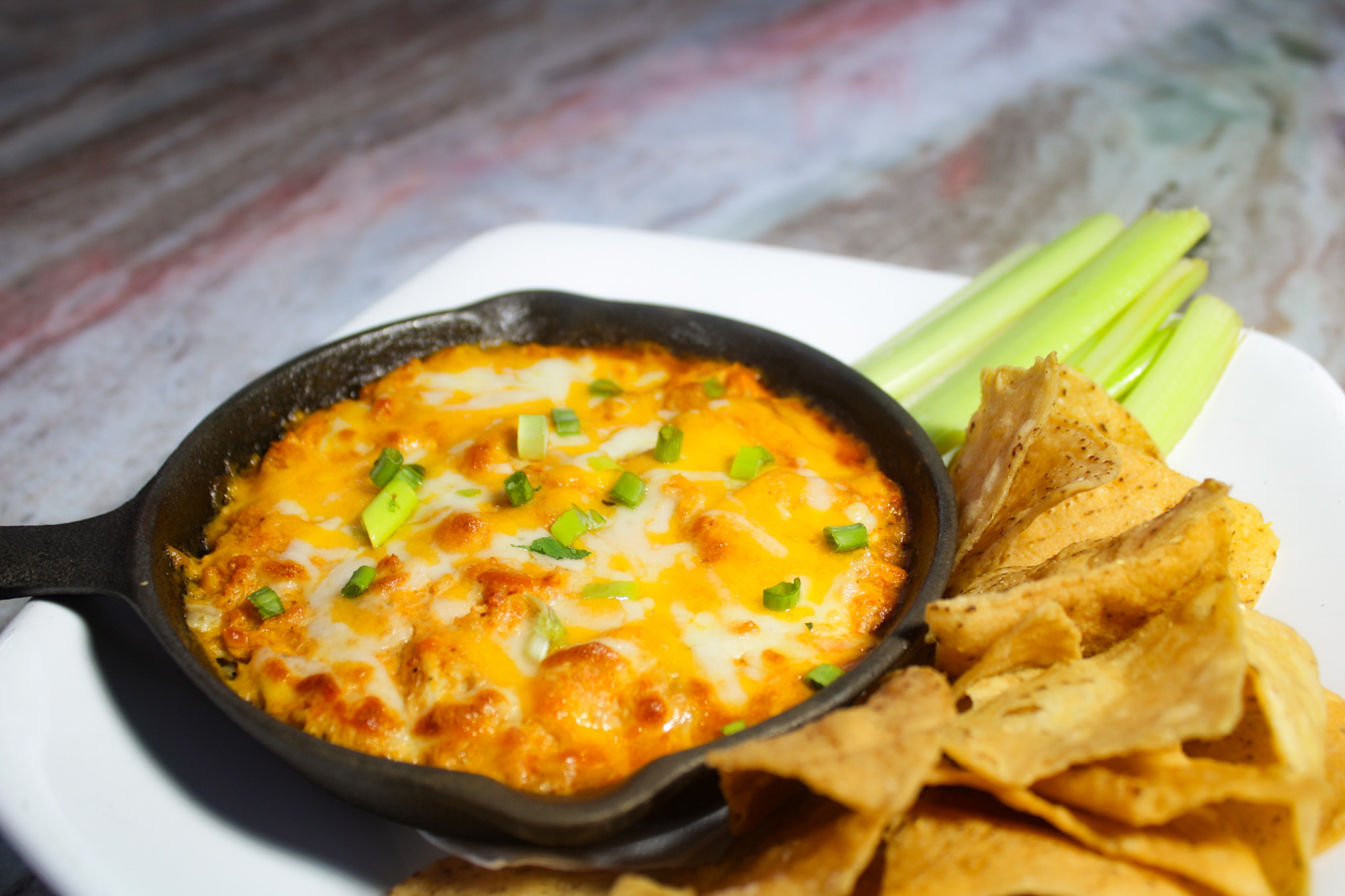 a plate of buffalo chicken dip with chips and celery