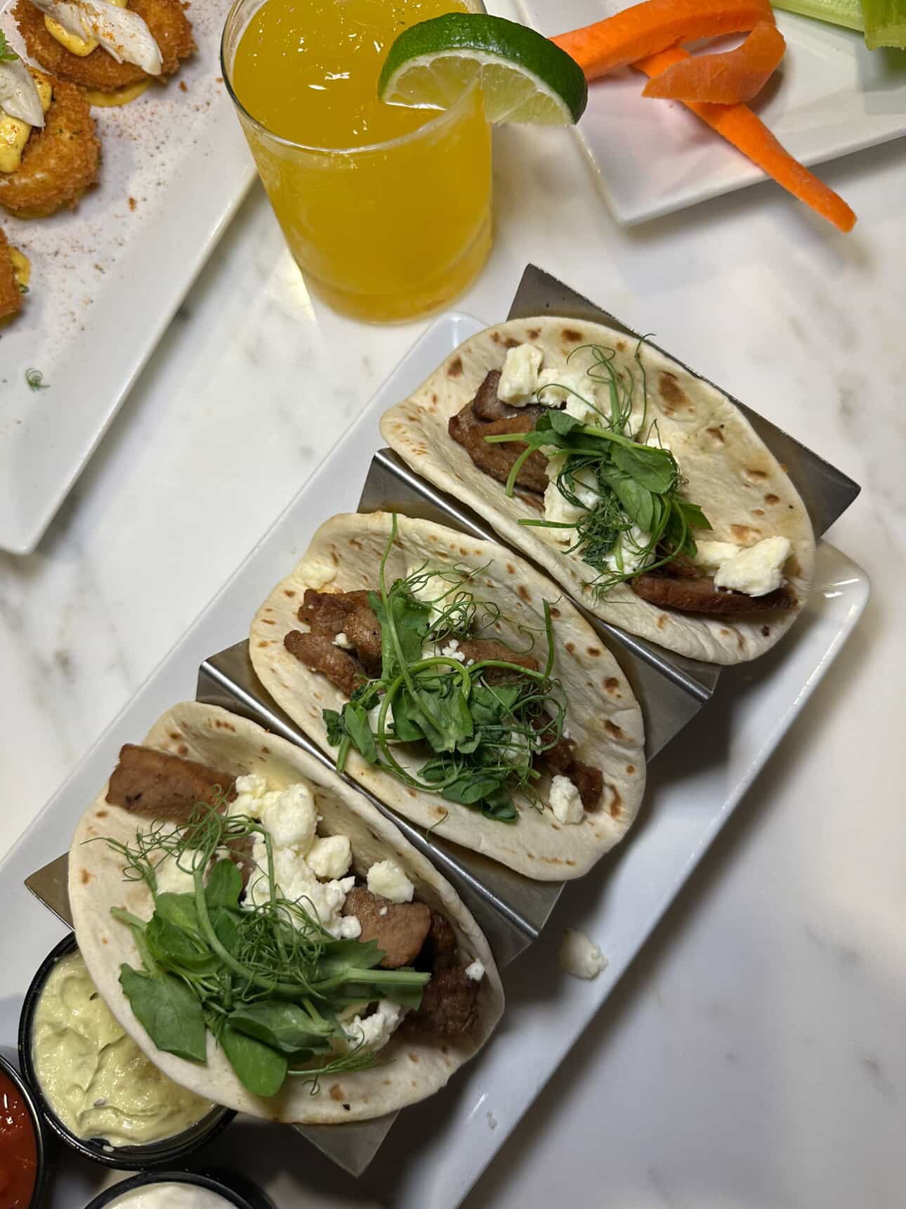 a plate of three tacos and a drink